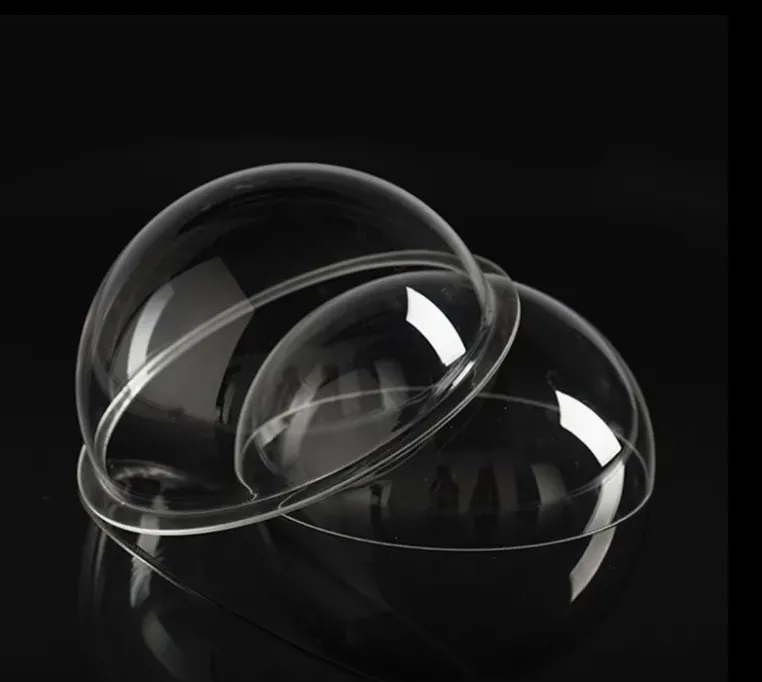 Clear acrylic domes with polished flanged edges on a black surface